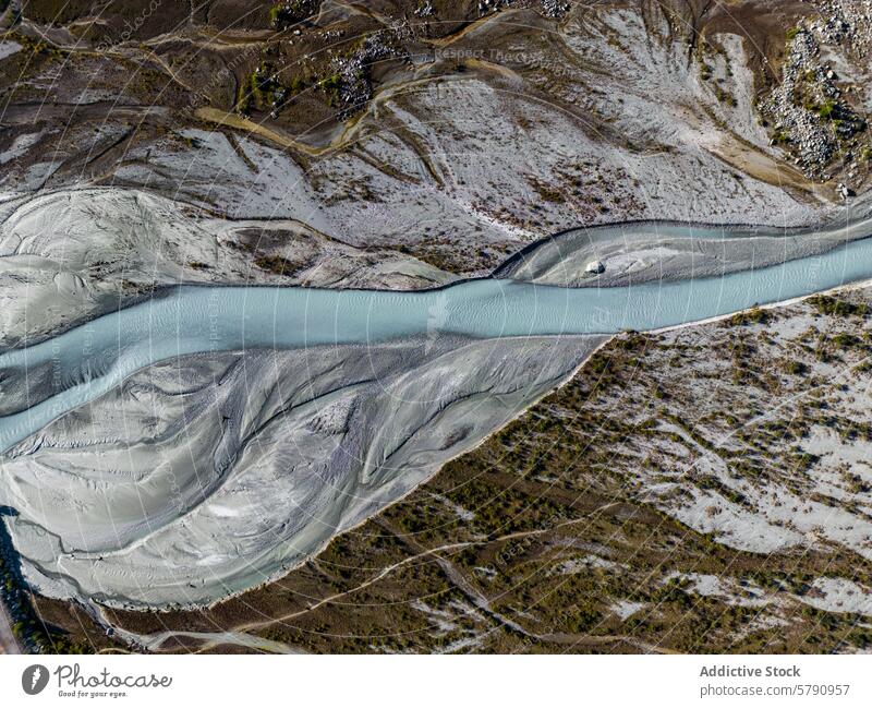 Hochauflösende Luftaufnahme, die einen gewundenen Gebirgsfluss zeigt, der sich durch eine strukturierte Landschaft mit unterschiedlichem Terrain schlängelt