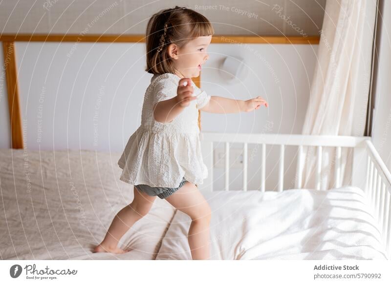 Kleines Mädchen spielt auf einem Bett in einem sonnigen Zimmer Kind spielen Schlafzimmer Sonnenlicht gemütlich Spaß spielerisch jung Unschuld im Innenbereich
