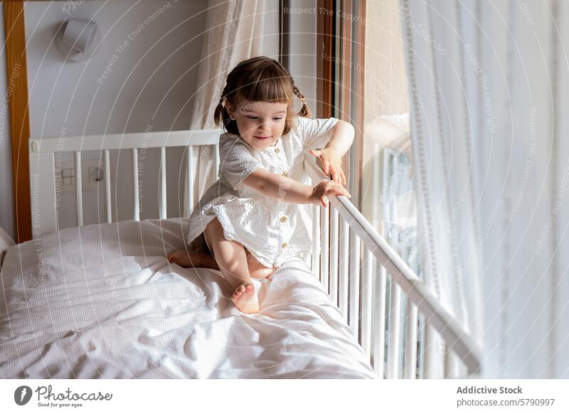 Kleinkindmädchen genießt die Spielzeit auf einem sonnenbeschienenen Bett Mädchen sonnig Fenster gemütlich Schlafzimmer heiter Kind Spielen im Innenbereich