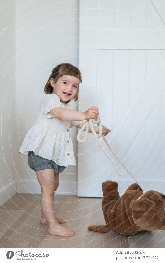 Verspieltes Kind mit einem Spielzeug in einem hellen Raum Kleinkind Mädchen spielen Plüsch im Innenbereich Freude Glück niedlich unschuldig modern lässig