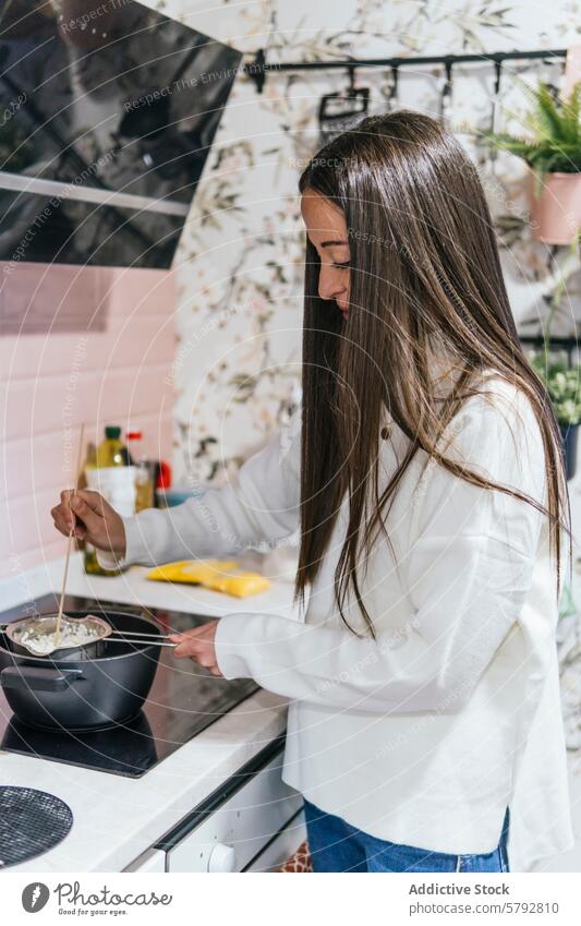 Frau kocht in einer stilvollen Küche Interieur Essen zubereiten Herd stylisch geblümt Tapete Innenbereich heimwärts Kochgeschirr Topf mitreißend