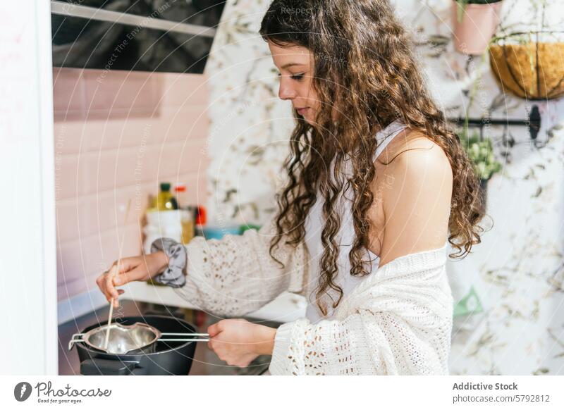 Junge Frau kocht aufmerksam in einer Wohnküche Essen zubereiten Küche heimwärts krause Haare mitreißend Topf Herd Fokus gemütlich Lockenhaarige jung