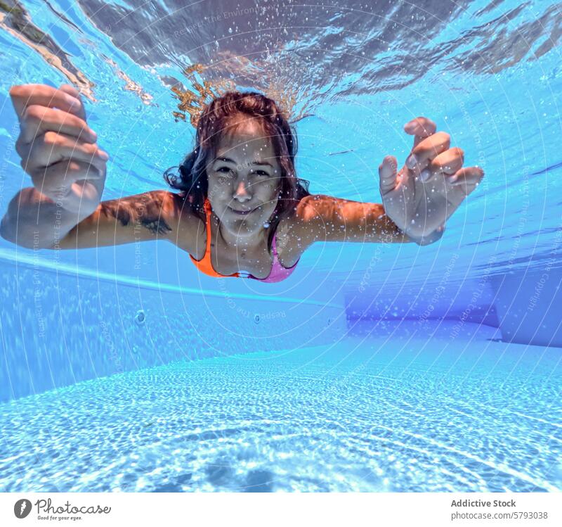 Unterwasseransicht einer Frau, die in einem Pool schwimmt unter Wasser Schwimmsport schwimmen übersichtlich blau Gelassenheit Lächeln erreichend Fotokamera