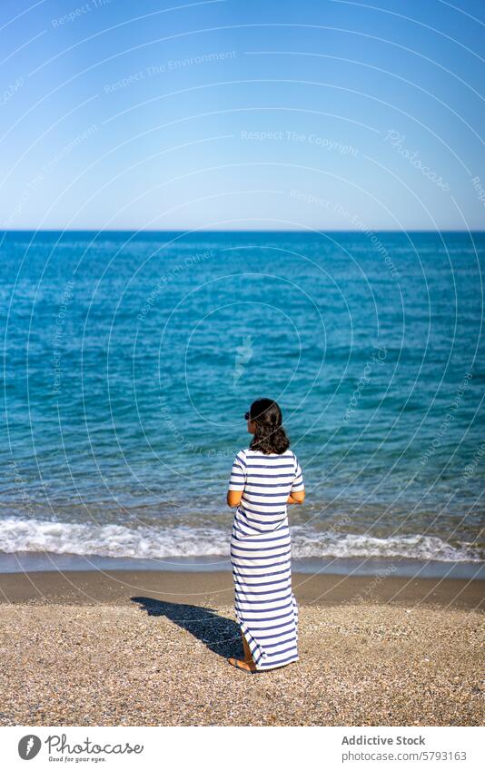 Frau mit Blick auf das Meer in Sardinien MEER Italien Strand mediterran Wasser Küste übersichtlich Kieselsteine Kleid gestreift blau Horizont Sommer reisen