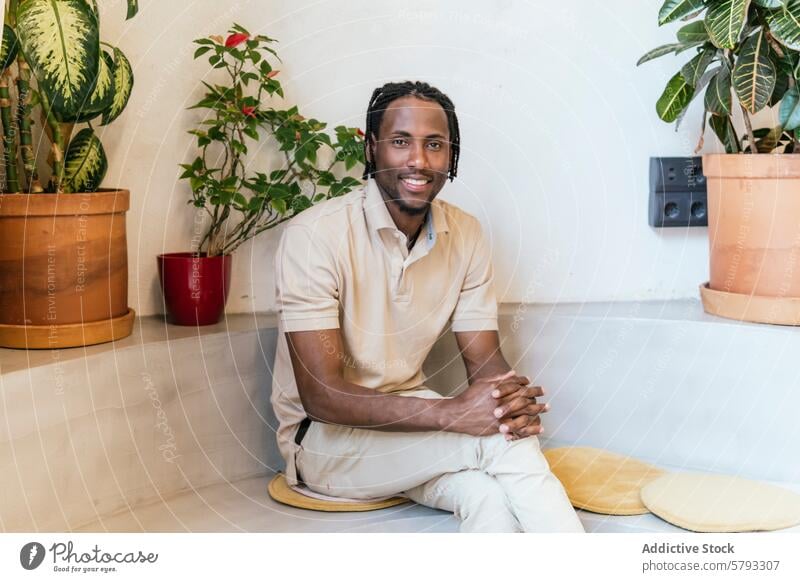 Entspannter Unternehmer in einem mit Pflanzen gefüllten Coworking Space cowoorking ethnisch Afroamerikaner Schwarzer Mann Lächeln Raum im Innenbereich modern