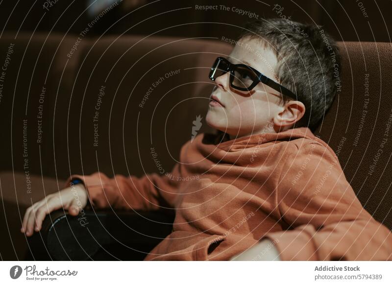Junge mit Brille sieht sich im Sommer einen Film an zuschauend im Innenbereich Sofa Freizeit Aktivität sitzend Kind jung Bildschirm Entertainment Filmmaterial