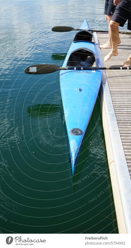 Rennsport Boot Kajak Zweier mit Paddel am Steg, zwei Sportler beim Einstieg Kanu Kanu-Rennsport Blau Wasser Fahrt auf dem Fluß Wassersportart Gewässer Füße