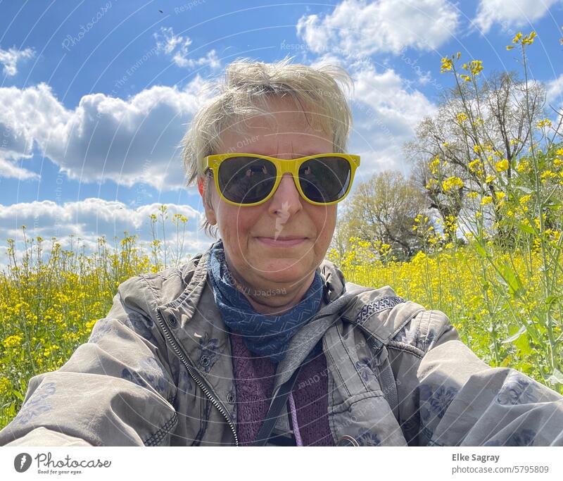 Blonde Frau mit gelber Sonnenbrille vor einem Rapsfeld blond feminin gelbe Sonnenbrille Nahaufnahme Erwachsene schön Mensch Tag Farbfoto Coolness Außenaufnahme