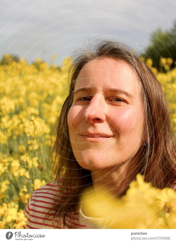 eine lächelnde Frau im Rapsfeld raps rapsfeld landwirtschaft ökologische landwirtschaft gelb anbau pflanzen Nutzpflanze Rapsblüte Frühling Natur Blüte frau