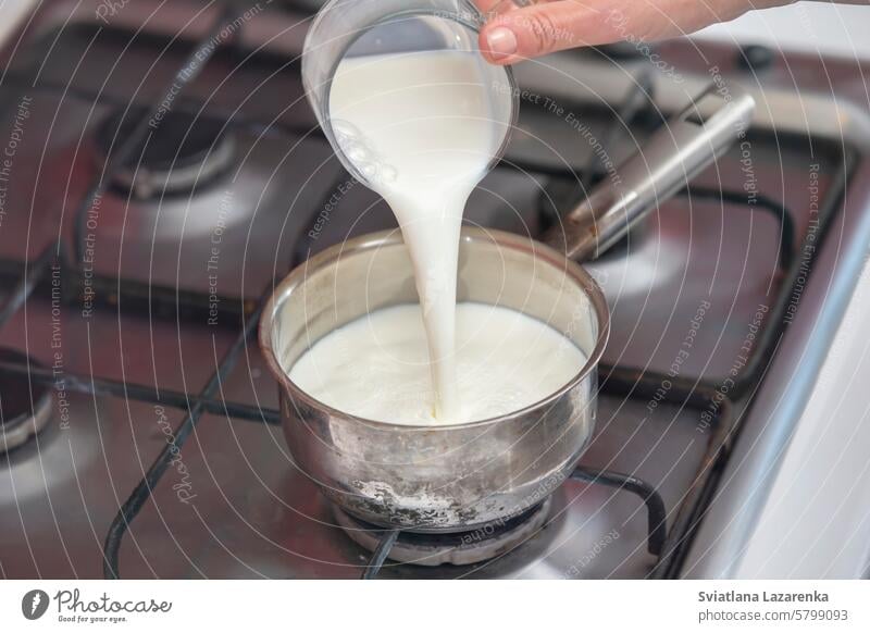Milch in einem kleinen Topf auf dem Herd zum Kochen bringen. Milchbrei zubereiten. Lebensmittel frisch Küche selbstgemacht Herstellung Hand vorbereiten weiß