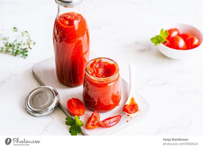 Passierte Tomaten in einem Einmachglas auf einem weißen Tisch püriert Tomatensauce Ketchup selbstgemacht Haltbarkeit Lebensmittel Gemüse lecker frisch rot