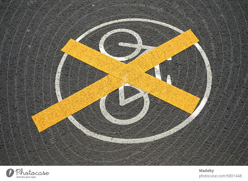 Gelb durchkreuzte weiße Markierung mit weißem aufgemaltem Verkehrszeichen auf dem grauen Asphalt eines Radweg in der Innenstadt der Messestadt Leipzig im Freistaat Sachsen