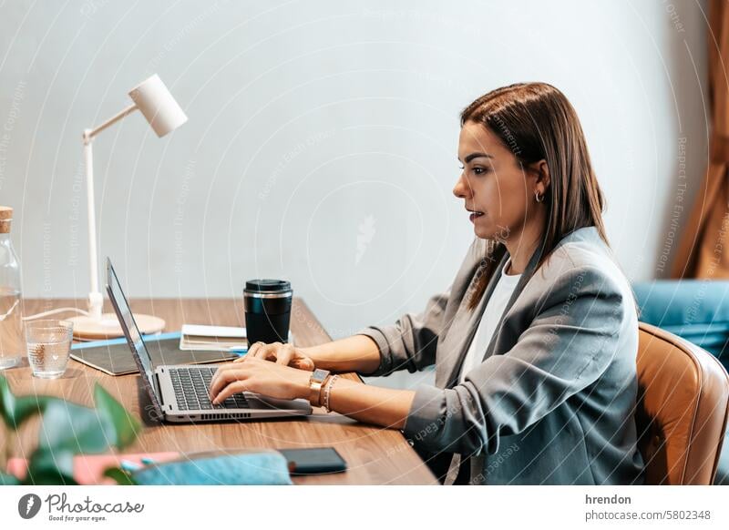 Frau arbeitet in einem Büro und tippt auf einem Laptop Geschäftsfrau Business Tippen arbeiten benutzend im Innenbereich fokussiert Cyberspace Unternehmer