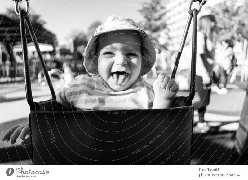 Porträt eines neun Monate alten Babys, das sich auf einer Schaukel vergnügt Kleinkind pendeln Park Fröhlichkeit lustig Glück Junge spielen Schule Vorschule