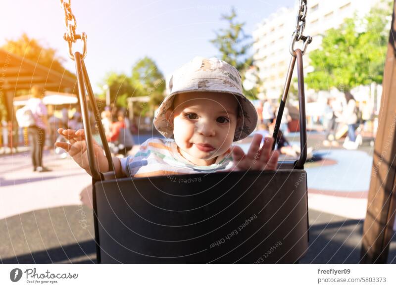 Porträt eines neun Monate alten Babys, das sich auf einer Schaukel vergnügt Kleinkind pendeln Park Fröhlichkeit lustig Glück Junge spielen Schule Vorschule