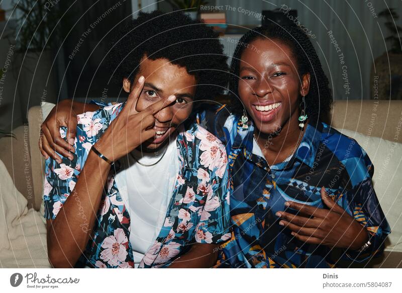 Fröhliches schwarzes Paar in geblümten Hemden macht Selfie zu Hause Spaß Frieden Menschen posierend Schwarzer Mann schwarze Frau Freund Freundin heimwärts Glück