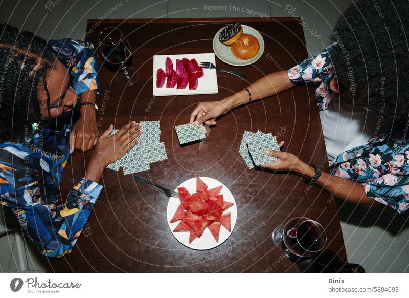 Black couple playing cards and eating fruits, view from the top game snack tasty hands watermelon sweet wine alcohol rest relax fun leisure hangout group friend