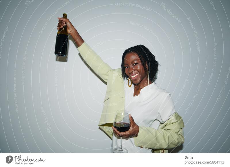 Portrait of young Black woman having bottle of red wine on Friday night celebration promotion drink party portrait office celebrate friday businesswoman