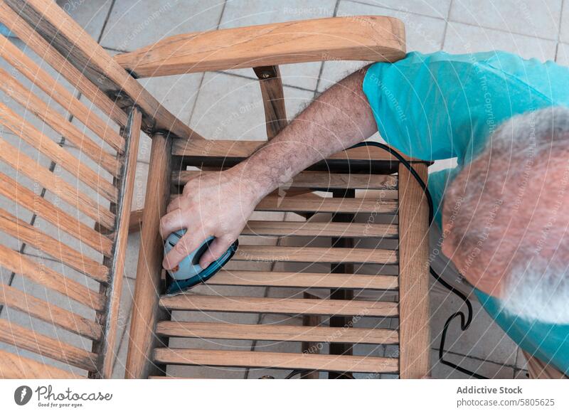 Mann renoviert alten Holzstuhl mit Schleifmaschine Schleifen Lackierung Möbel hölzern Stuhl Restauration Renovierung von elektrisch Nacharbeiten Holzarbeiten