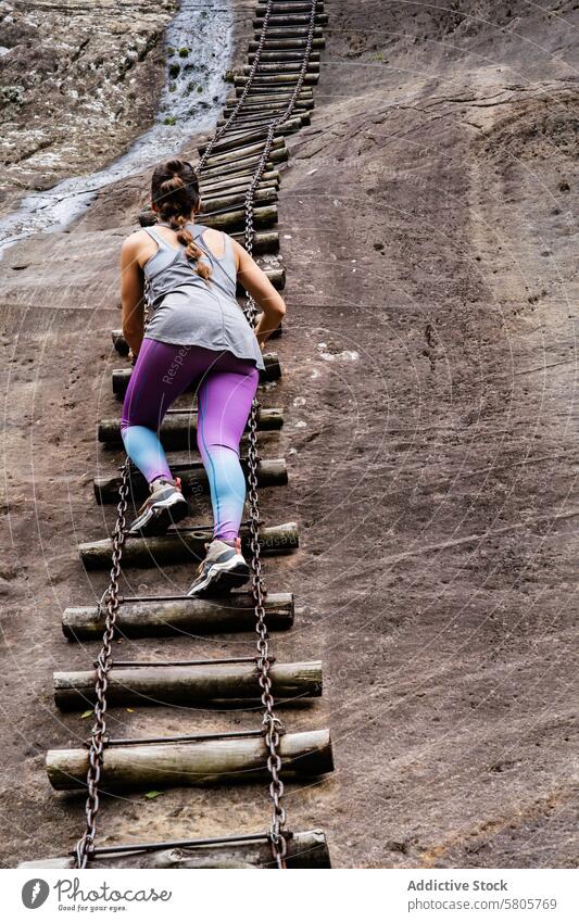 Abenteuerlustiger Wanderer klettert auf eine schroffe Bergleiter Frau Klettern Berge u. Gebirge Laufmasche Tatkraft steil hölzern Metall anketten im Freien