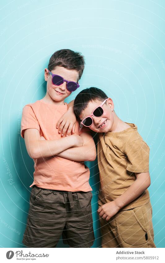 Zwei glückliche Schuljungen posieren mit Sonnenbrille Jungen Schule Kind Lächeln Glück heiter Selbstvertrauen Pose Blauer Hintergrund in die Kamera schauen