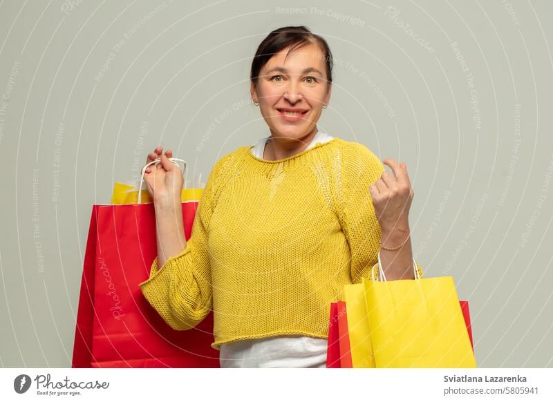 Porträt einer glücklichen erwachsenen Frau mit Geschenktüten auf grauem Hintergrund.Shopper. Person Taschen Mode Sale attraktiv Schönheit kaufen Laden Lifestyle