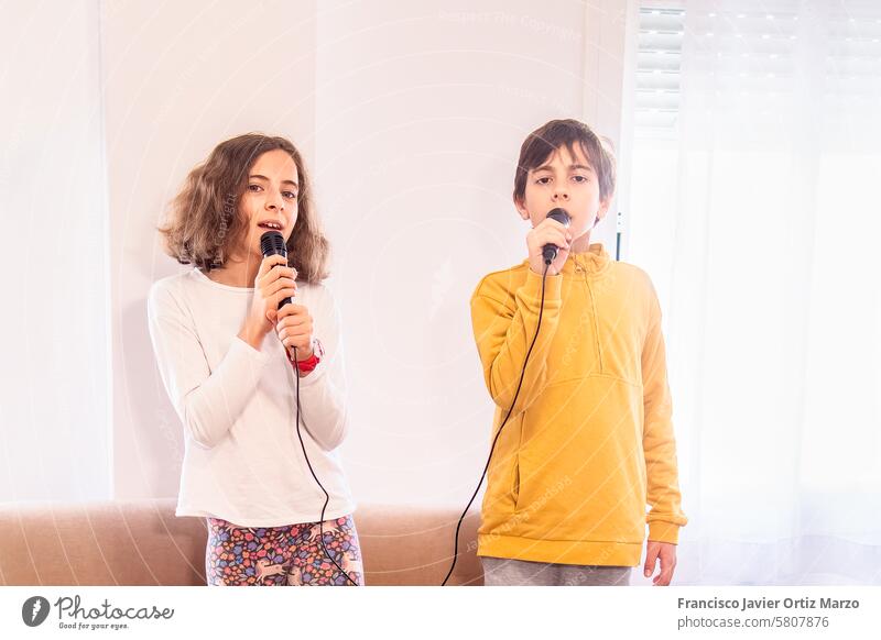 Kinder singen gemeinsam in Mikrofone zwei Gesang Leistung Musik Leidenschaft Entertainment Spaß Ausdruck Talent Sängerin Duett Freude Schnur Raum Licht lässig