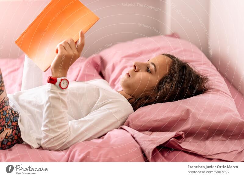 Junges Mädchen liest Buch in rosa Bett jung lesen Komfort sich[Akk] entspannen heimwärts Freizeit Bildung Literatur Jugend Schlafzimmer gemütlich Lernen lernen