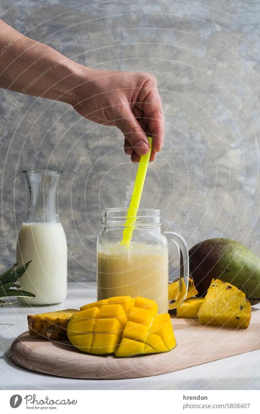 Rühren eines Mango-Ananas-Smoothies mit einem Strohhalm trinken Lebensmittel Frucht organisch Gesundheit Frühstück Saft Glas Diät Cocktail Getränk gemischt
