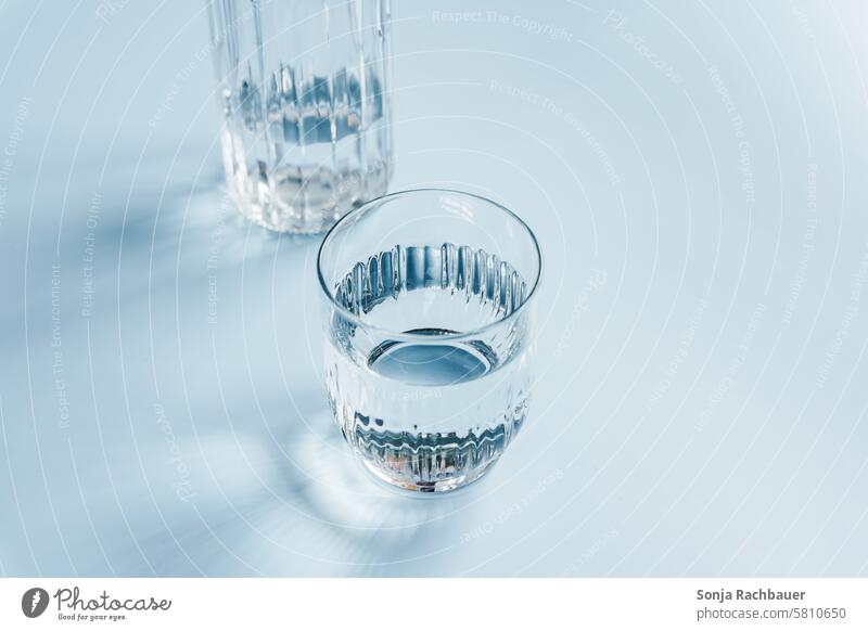 Ein Glas Wasser und eine Karaffe auf einem blauen Tisch Trinkglas Schlagschatten Wasserglas Trinkwasser Getränk Erfrischungsgetränk Mineralwasser Flüssigkeit