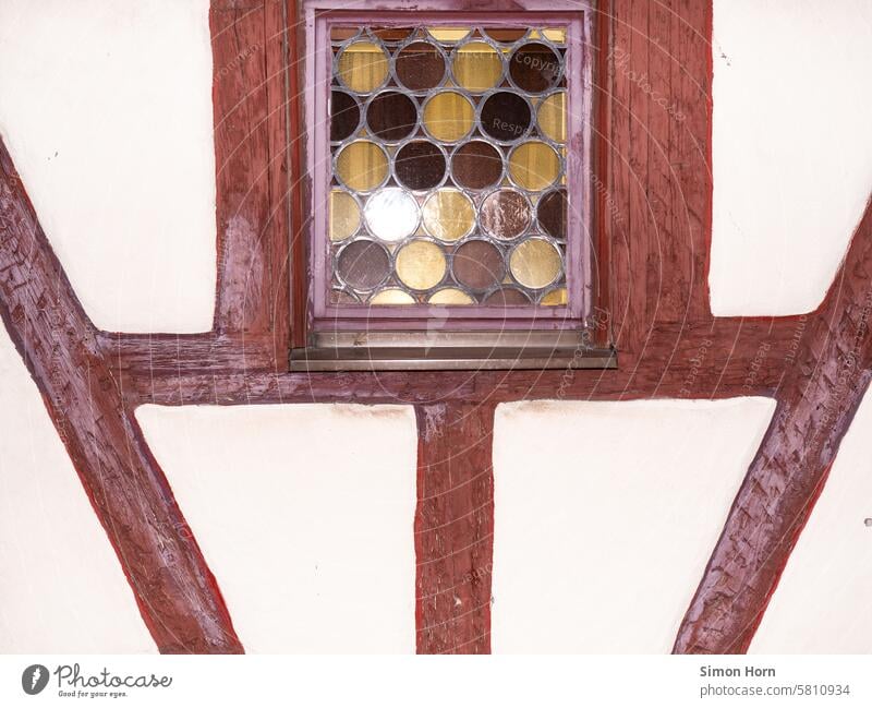 Detail eines Fachwerkhauses, in der oberen Bildmitte befindet sich ein Fenster mit einer mehrfarbigen Butzenscheibe historisch Altstadt alt Fassade Bauwerk
