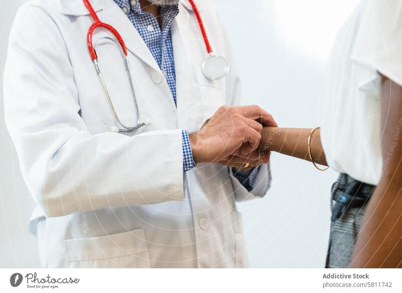 Älterer Arzt misst den Puls eines Patienten messen geduldig prüfen Ernennung untersuchen Krankenhaus Gesundheitswesen besuchen multiethnisch rassenübergreifend