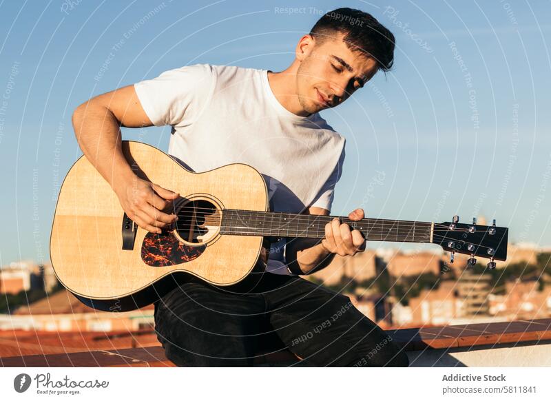 Junger Mann sitzt auf einem Dach und spielt Akustikgitarre Gitarre Musiker Gitarrenspieler akustisch jung Sitzen männlich Person Instrument Spieler Musical