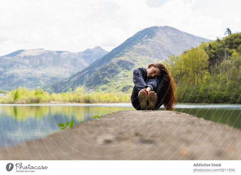 Reisende Frau sitzt auf einem Pier in der Nähe eines Sees im Hochland Berge u. Gebirge Teich Reisender Wanderer Kai Trave
