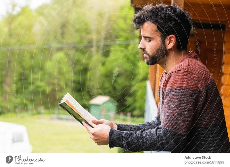 Nachdenklicher Mann liest ein Buch auf der Terrasse eines Hauses lesen Literatur interessant Hobby nachdenklich Roman männlich Pyrenäen hölzern ruhen Windstille