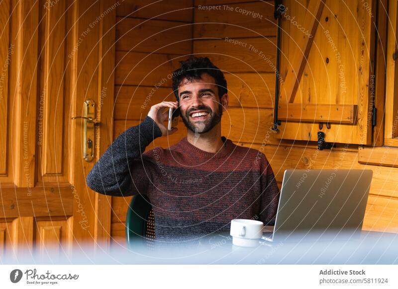 Fröhlicher Mann, der mit seinem Smartphone spricht und auf der Terrasse arbeitet reden Arbeit abgelegen sprechen Mobile Telefon freiberuflich männlich Pyrenäen