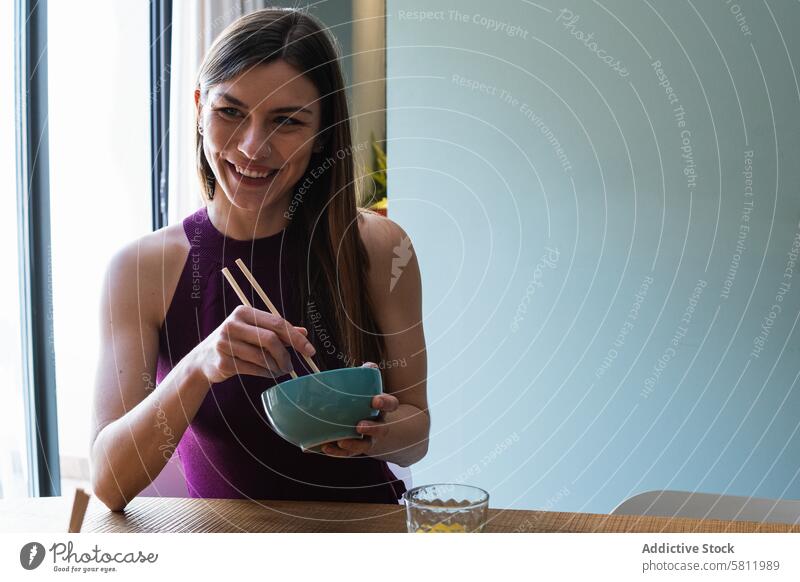 Fröhliche Frau mit Essstäbchen beim Mittagessen im Speisesaal Lebensmittel Glück Zahnfarbenes Lächeln lecker genießen Mahlzeit Asiatische Küche hungrig
