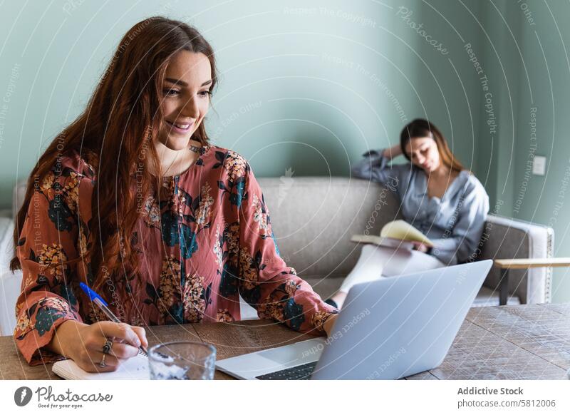 Konzentrierte Frau macht sich Notizen und arbeitet am Laptop Frauen Arbeit zur Kenntnis nehmen Fokus beschäftigt Konzentration schreiben Cowork benutzend lesen