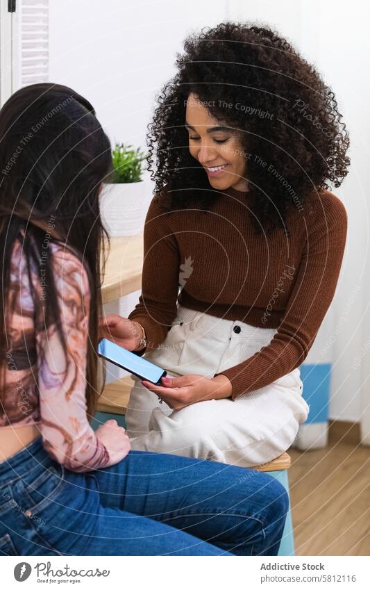 Unterschiedliche Frauen benutzen gemeinsam ein Smartphone in einer Bar Freund Zusammensein Kälte benutzend Mobile Telefon Abfertigungsschalter multiethnisch