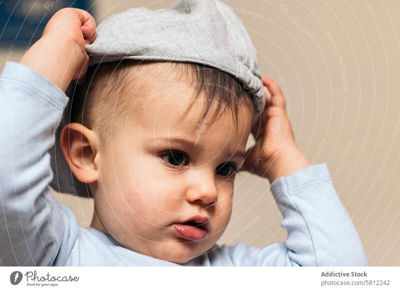 Süßes Baby, das sich zu Hause eine Mütze aufsetzt Kind niedlich Hut Kindheit wenig Glück klein weiß Unschuld bezaubernd heiter schön Kaukasier Porträt