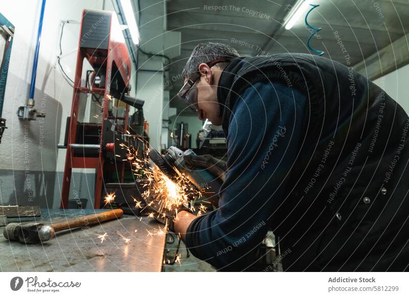 Fokussierter Automechaniker beim Polieren von Metall in der Werkstatt Mann polnisch Mechaniker Schweißnaht Funken Garage Arbeit Gerät Fähigkeit Heimwerker