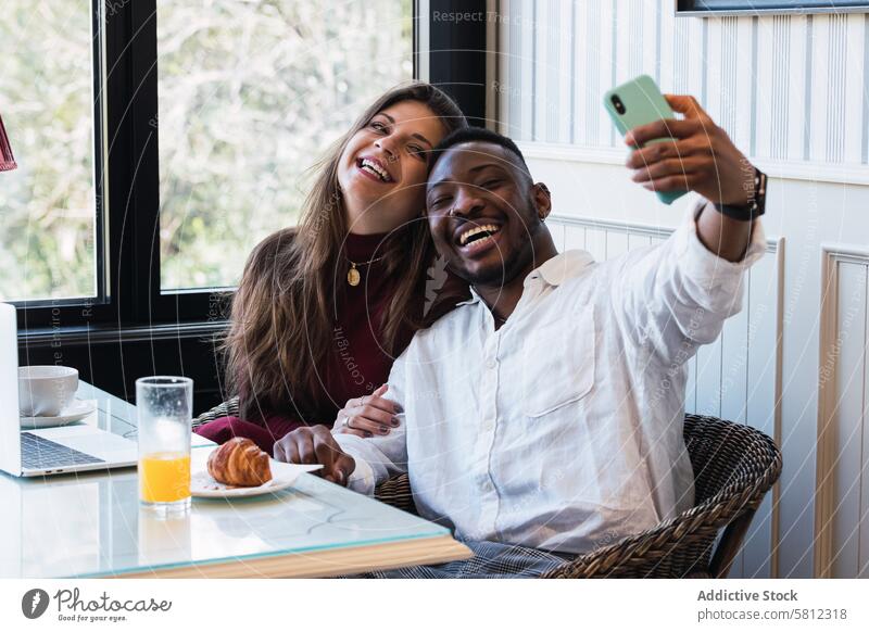 Fröhliches multiethnisches Paar, das zu Hause einen Laptop benutzt und ein Selfie macht benutzend Zusammensein Glück heiter Browsen Partnerschaft Liebe