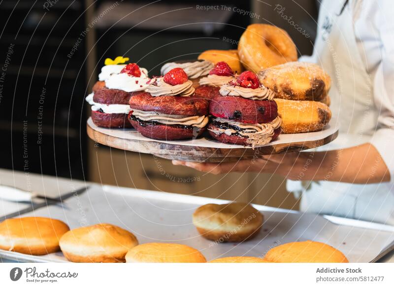 Frau mit Berliner auf dem Tablett in einer Bäckerei Veganer berliner Dessert geschmackvoll sortiert Küche kulinarisch lecker Feinschmecker Uniform frisch