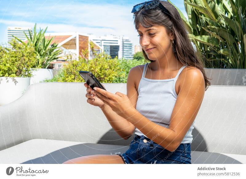 Eine Frau schaut im Freien auf ihr Smartphone. modern Erwachsener App attraktiv schön Browsen Business lässig Kaukasier Zelle Funktelefon Großstadt Mitteilung