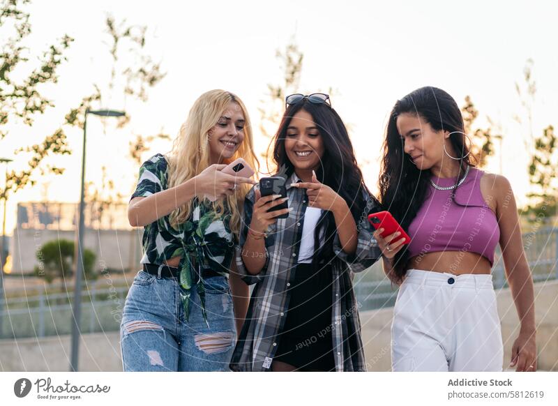 Mädchen gehen auf der Straße und benutzen Smartphones Glück jung Sommer Frau im Freien Menschen Freizeit Lifestyle freudig Freude Blick Frühling Genuss