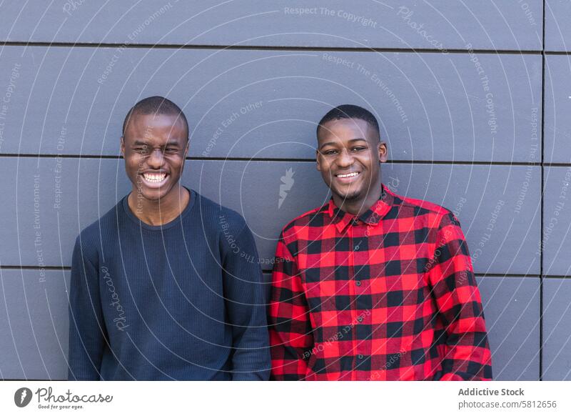 Glückliche schwarze männliche Freunde vor grauer Wand Männer Persönlichkeit Lächeln Starrer Blick selbstbewusst Individualität Jugend Vorschein starren