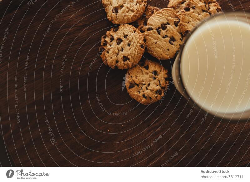 Die Einfachheit genießen: Selbstgebackene Kekse mit einem Glas Milch auf einem eleganten Holztisch. hausgemachte Kekse Komfortnahrung Klassischer Leckerbissen