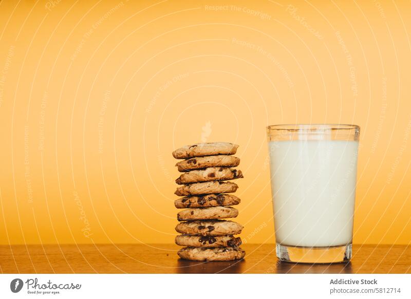 Leckeres Frühstück: Kekse und Milch auf einem Holztisch mit orangefarbenem Hintergrund. Frühstücksfotografie Food-Styling Bilder von Keksen und Milch
