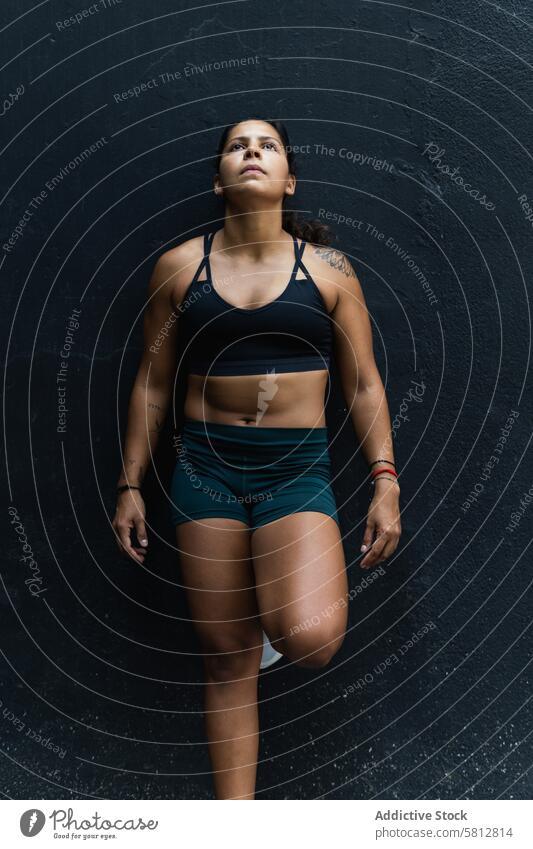 Hispanische Sportlerin an der Wand stehend Frau sportlich Sportkleidung Training Gesunder Lebensstil Wellness Fitness muskulös Straße Dame die Arme verschränkt