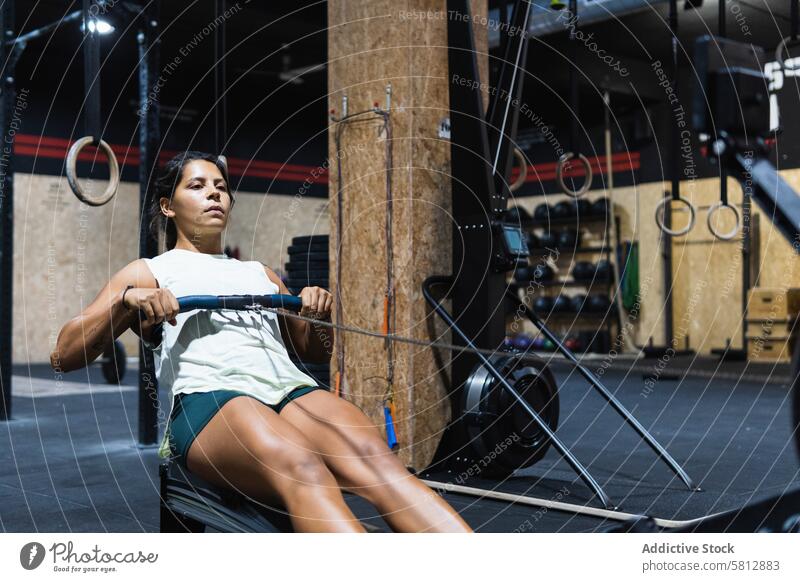 Hispanische Sportlerin trainiert auf einem Rudergerät Reihe Maschine Training Fitnessstudio Übung Gewichtheben üben sportlich Frau Sportkleidung Sportbekleidung